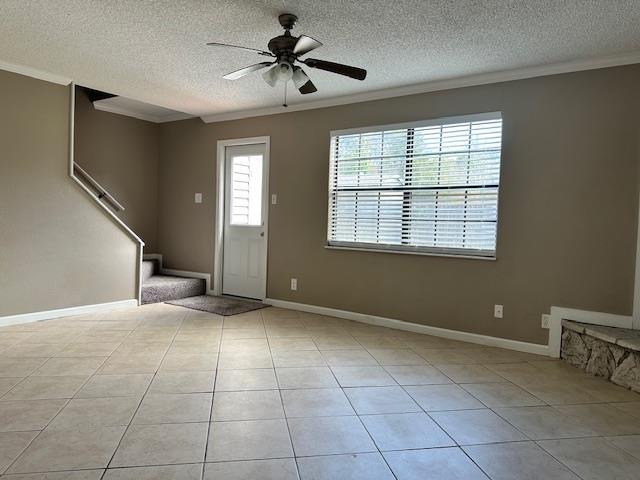 entrance foyer featuring light tile patterned floors, a textured ceiling, ceiling fan, and crown molding