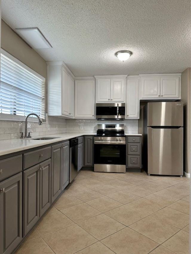 kitchen featuring white cabinets, appliances with stainless steel finishes, gray cabinets, and sink