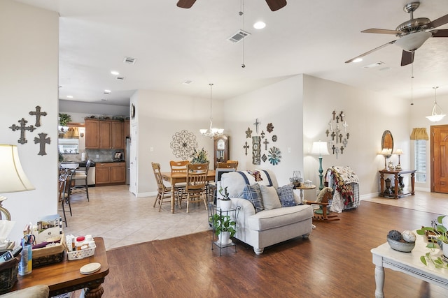 living room with light hardwood / wood-style floors and ceiling fan with notable chandelier