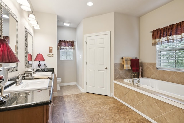 bathroom featuring tiled tub, vanity, and toilet