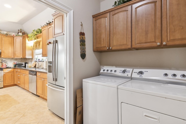 clothes washing area with cabinets, washing machine and dryer, light tile patterned floors, and sink