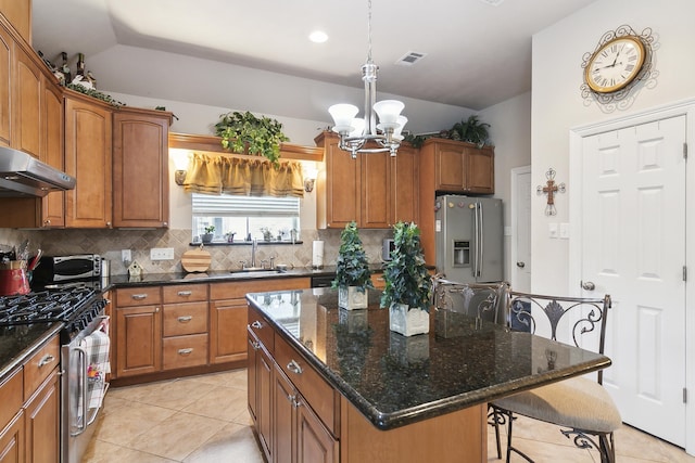 kitchen featuring a center island, an inviting chandelier, tasteful backsplash, light tile patterned floors, and appliances with stainless steel finishes