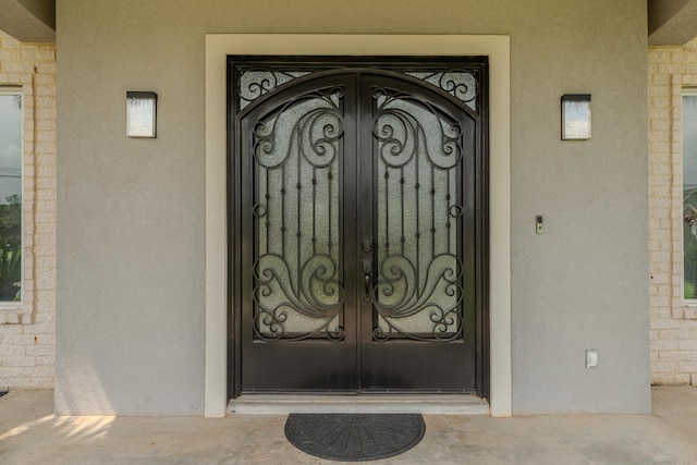 view of exterior entry featuring french doors and stucco siding