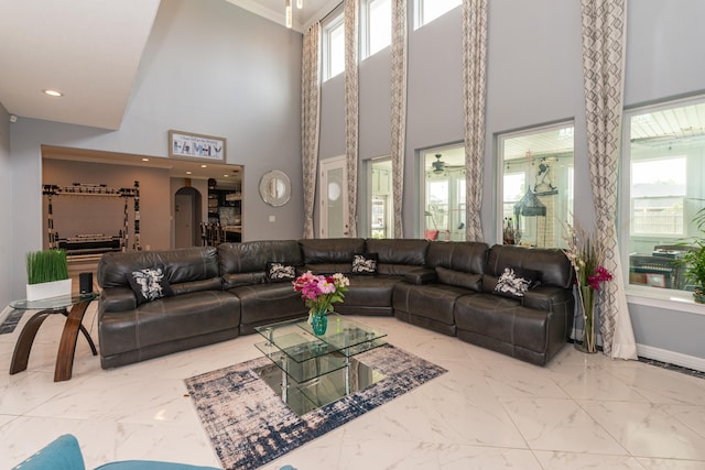 living area featuring arched walkways, marble finish floor, recessed lighting, and baseboards