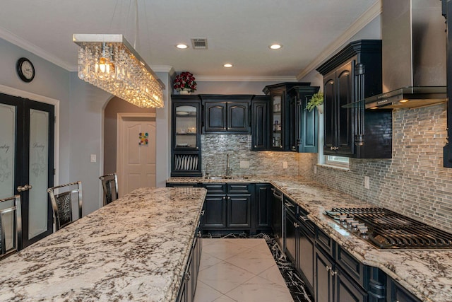 kitchen featuring arched walkways, stainless steel gas cooktop, visible vents, a sink, and wall chimney exhaust hood