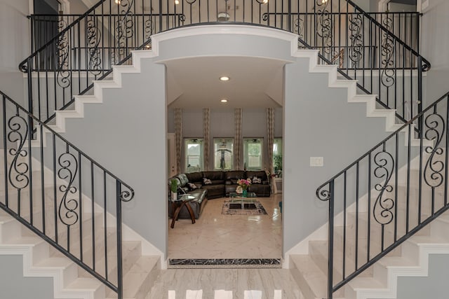 foyer entrance with marble finish floor, stairs, a high ceiling, and recessed lighting