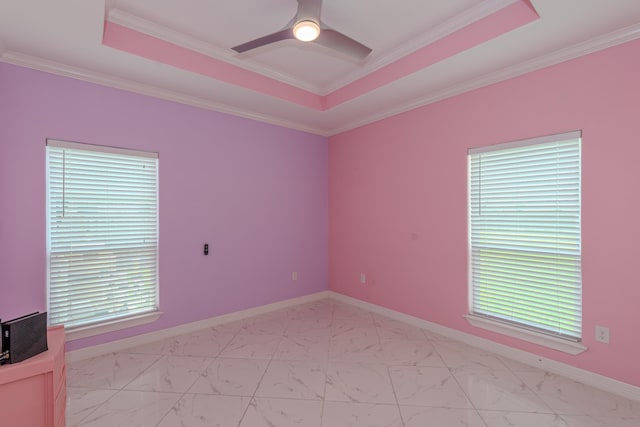 empty room with marble finish floor, a tray ceiling, a ceiling fan, and baseboards