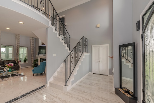 entryway featuring stairs, marble finish floor, a towering ceiling, and baseboards