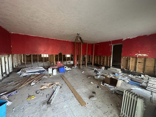 misc room with radiator heating unit and a textured ceiling