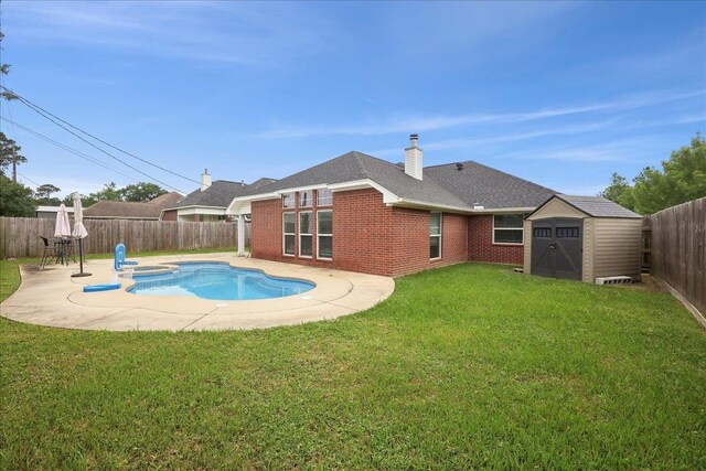 view of pool with a patio area, a shed, a lawn, a fenced backyard, and an outbuilding