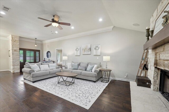 living area with hardwood / wood-style flooring, ceiling fan, crown molding, and a stone fireplace