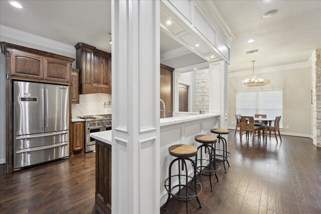 kitchen with an inviting chandelier, dark wood-style flooring, stainless steel appliances, and light countertops