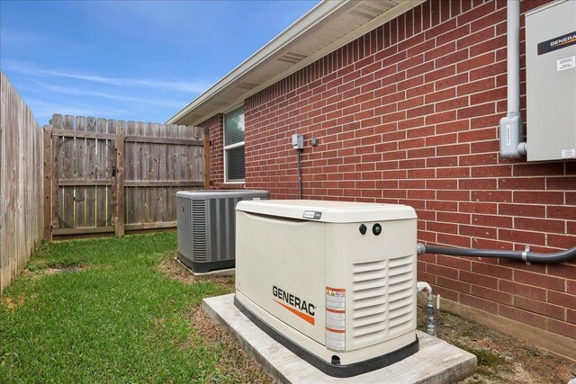 details featuring a power unit, fence, brick siding, and central air condition unit