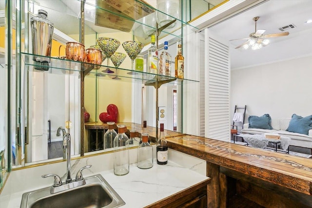 bar featuring ornamental molding, ceiling fan, and sink