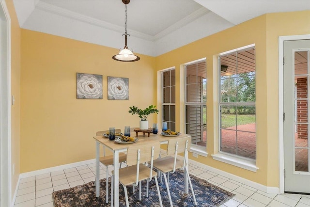 tiled dining area with a raised ceiling and crown molding