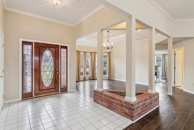 foyer entrance with ornate columns, an inviting chandelier, ornamental molding, and hardwood / wood-style flooring