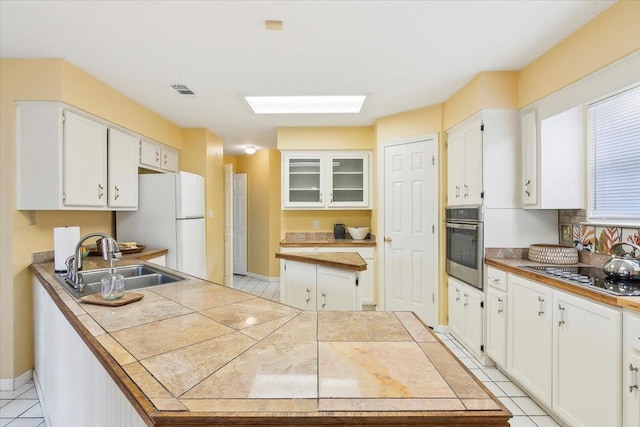 kitchen with sink, white cabinets, tile countertops, and appliances with stainless steel finishes