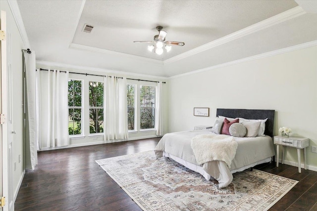 bedroom featuring crown molding, ceiling fan, dark wood-type flooring, a tray ceiling, and a textured ceiling