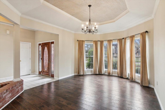 foyer entrance with ornamental molding, a raised ceiling, a chandelier, and hardwood / wood-style flooring