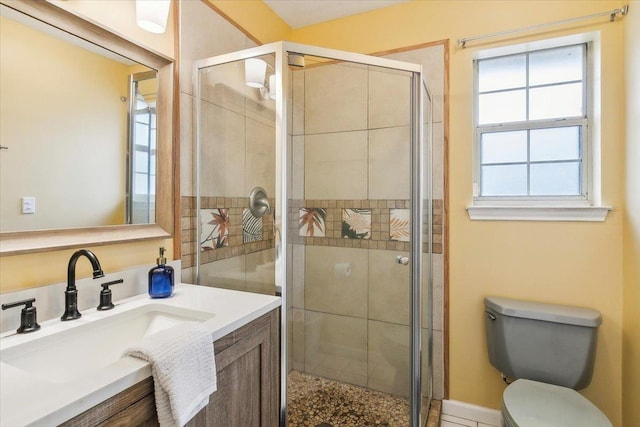 bathroom with a healthy amount of sunlight, a shower with door, vanity, and toilet