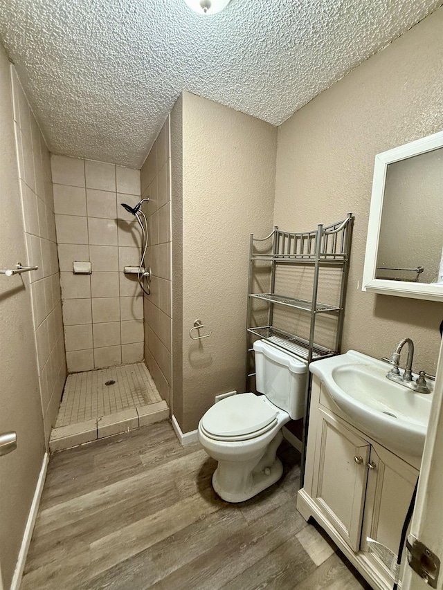 bathroom featuring a stall shower, toilet, wood finished floors, and a textured ceiling