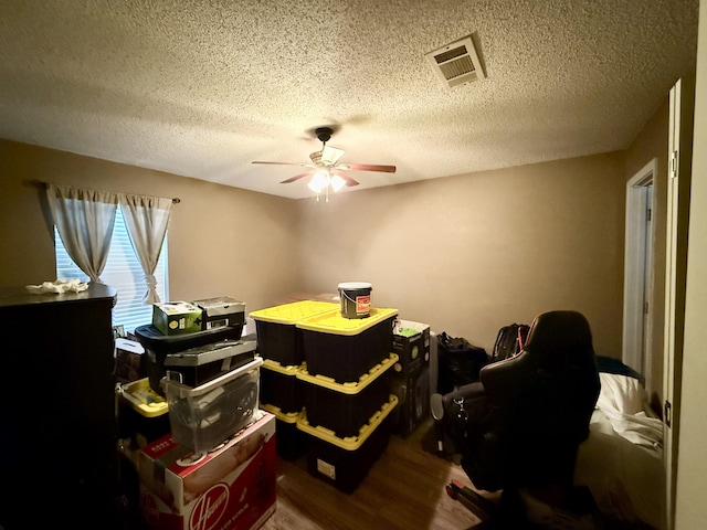 bedroom with visible vents, a textured ceiling, ceiling fan, and wood finished floors