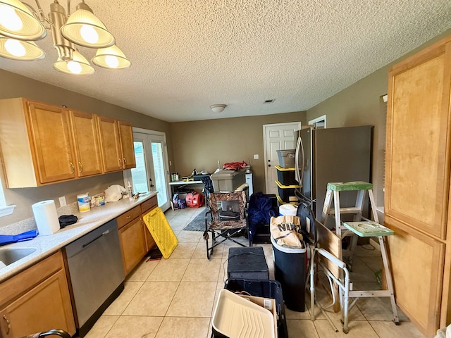 kitchen with light tile patterned floors, stainless steel dishwasher, a textured ceiling, and light countertops