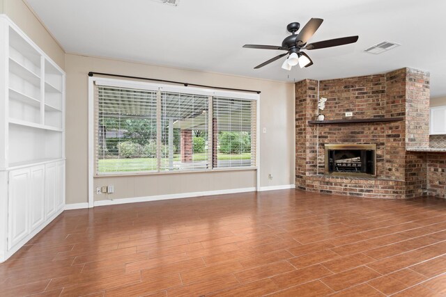 unfurnished living room featuring hardwood / wood-style flooring, ceiling fan, and a brick fireplace