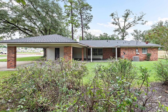 ranch-style home featuring a carport, a front yard, and central AC