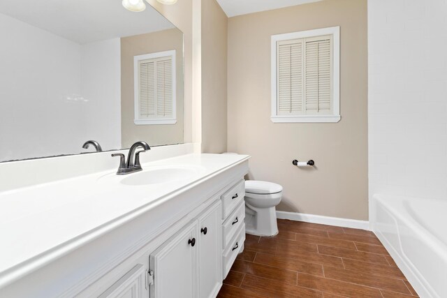 bathroom with vanity, toilet, and a tub