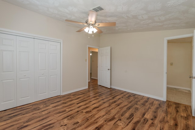 unfurnished bedroom featuring a textured ceiling, ceiling fan, dark wood-type flooring, a closet, and lofted ceiling