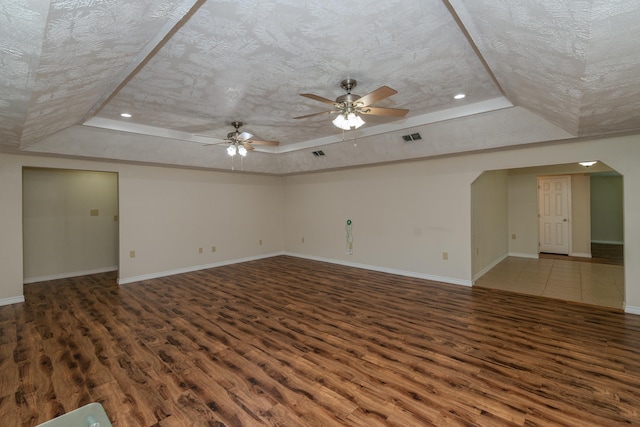 spare room with dark hardwood / wood-style floors, a raised ceiling, and ceiling fan