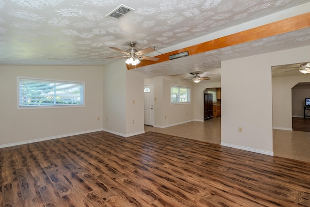 spare room featuring ceiling fan, plenty of natural light, dark wood-type flooring, and a textured ceiling