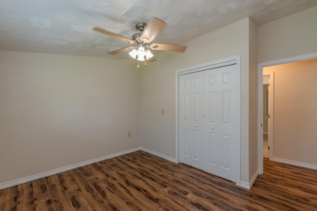 unfurnished bedroom with a textured ceiling, a closet, dark hardwood / wood-style floors, and ceiling fan