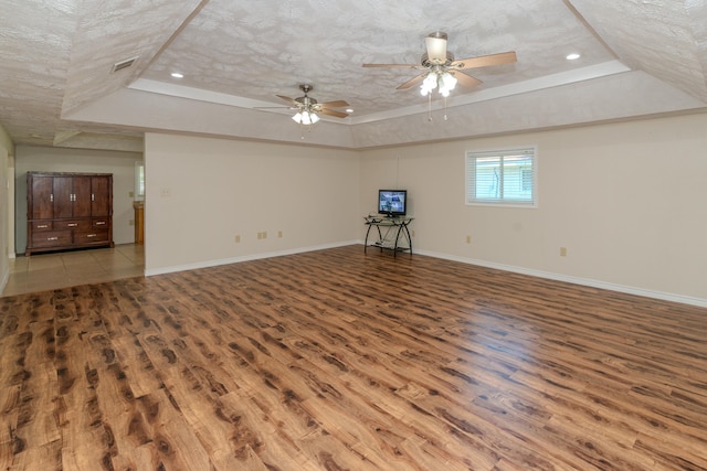 interior space with hardwood / wood-style flooring, ceiling fan, a textured ceiling, and a tray ceiling