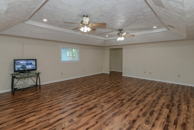 unfurnished living room with a tray ceiling, dark wood-type flooring, and a textured ceiling