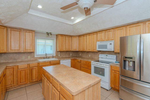 kitchen with a center island, white appliances, sink, light tile patterned floors, and a tray ceiling