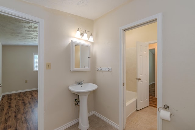 bathroom featuring hardwood / wood-style flooring, a tub to relax in, and a textured ceiling