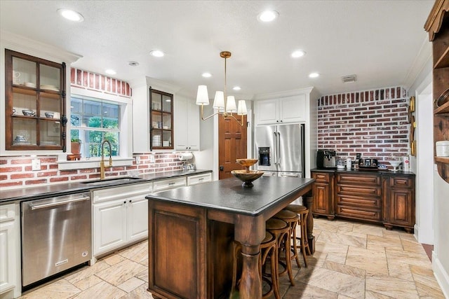 kitchen featuring white cabinets, a kitchen island, sink, and stainless steel appliances