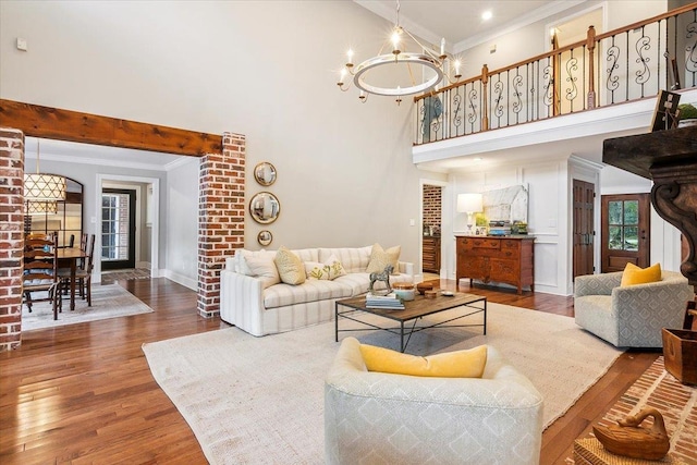 living room featuring ornamental molding, dark wood-type flooring, a notable chandelier, and a high ceiling