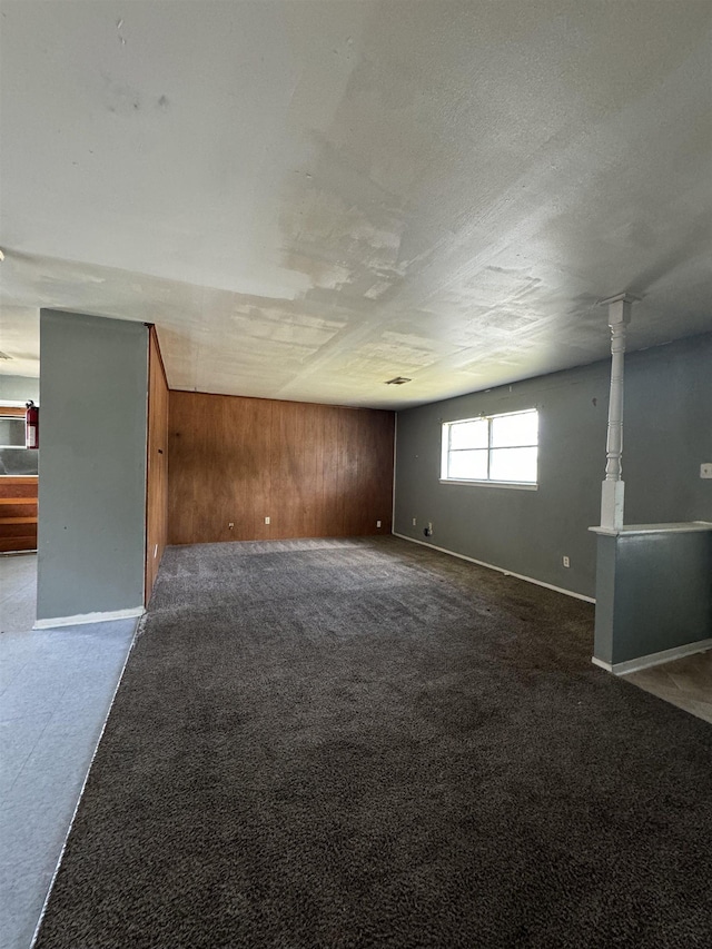 empty room featuring wood walls and dark colored carpet