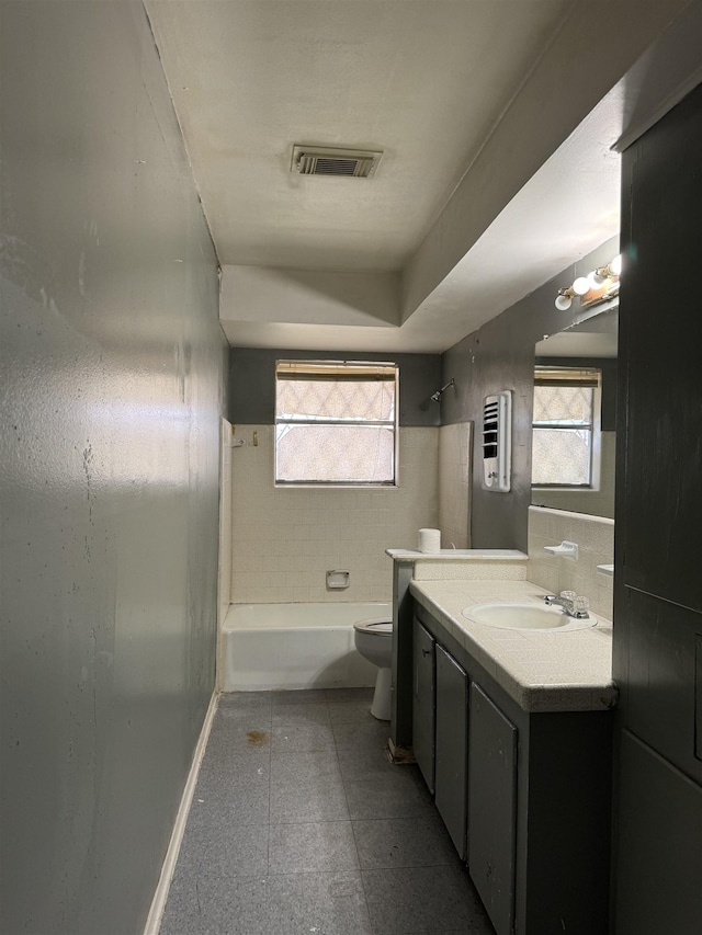 full bathroom featuring tiled shower / bath, a wealth of natural light, vanity, and toilet