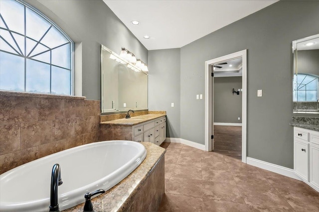 bathroom with vanity, plenty of natural light, and tiled bath