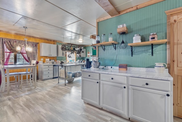 kitchen with dishwasher, wood walls, white cabinets, hanging light fixtures, and light hardwood / wood-style floors