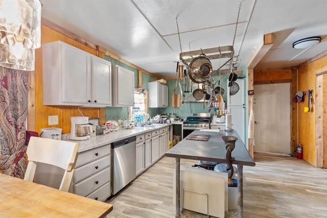 kitchen with sink, light hardwood / wood-style flooring, gray cabinets, wooden walls, and appliances with stainless steel finishes