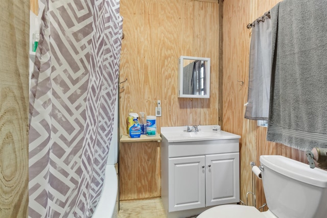 bathroom featuring vanity, toilet, and wood walls