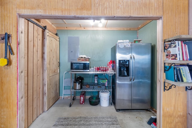 kitchen featuring a barn door, stainless steel appliances, wood walls, and electric panel