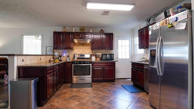 kitchen featuring a textured ceiling, stainless steel appliances, kitchen peninsula, and tasteful backsplash