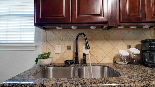 kitchen with dark stone countertops, tasteful backsplash, and sink