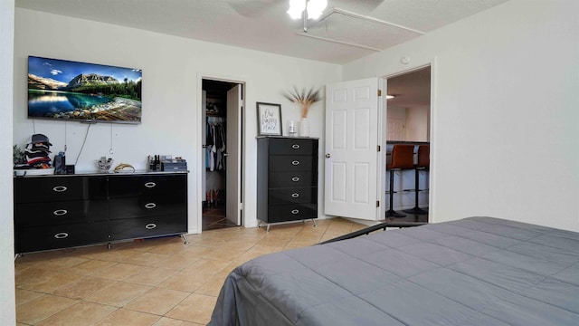 bedroom with a spacious closet, ceiling fan, connected bathroom, a closet, and light tile patterned flooring